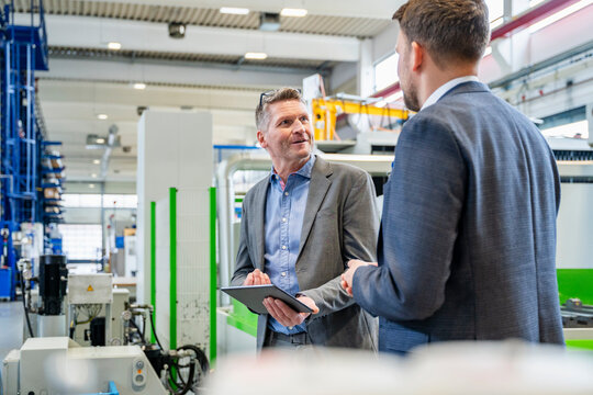 Managers discuss organization with tablet in production hall