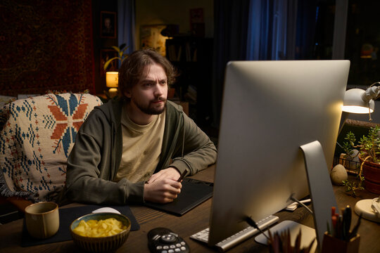 Freelancer drawing on graphics tablet at home office during night