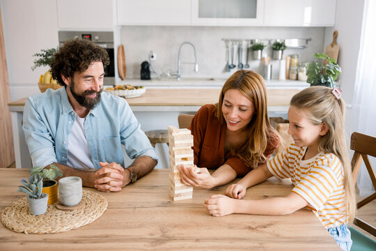 Family playing board game together at home in the kitchen
