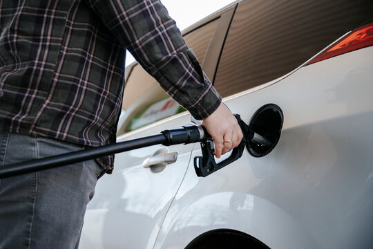 Driver refilling white car with diesel at gas station outdoors