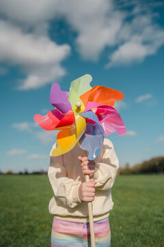 Child holding colorful pinwheel toy at the park on a sunny day