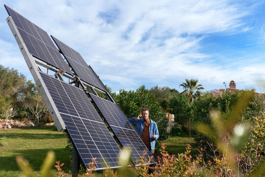 Man standing near solar panels and talking on smart phone