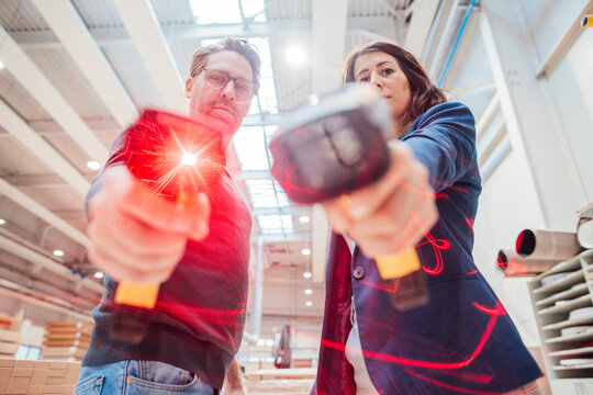 Colleagues showing illuminated bar code readers standing in workshop