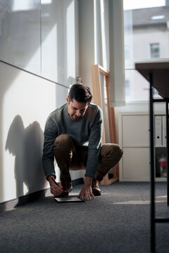 Businessman crouching and using tablet PC with digitized pen in office