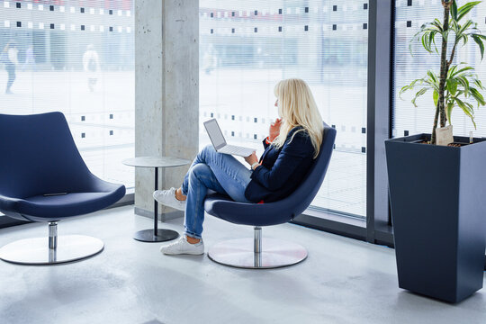 Blond businesswoman sitting with laptop on chair