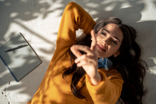 Young woman lying on floor and gesturing at home