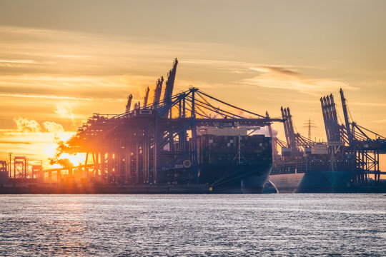 Container terminal and cargo ship in Hamburg harbour at sunrise
