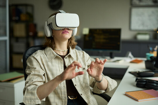 Programmer testing virtual reality headset at indoor office desk