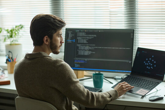 Programmer analyzing digital code on computer in the office