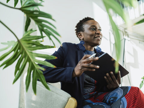 Businesswoman sitting on chair holding tablet PC at office