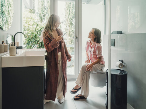 Sisters enjoying fun conversation while getting ready in bathroom