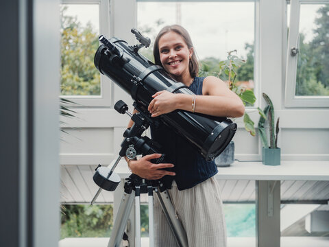 Smiling scientist with telescope indoors during daylight