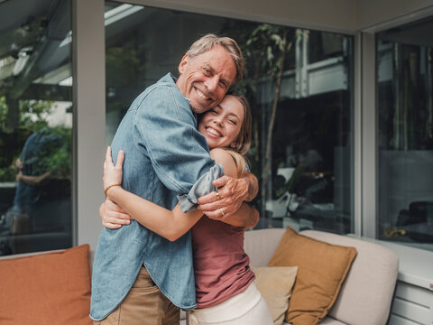 Father and daughter hugging with smiles at home in summer