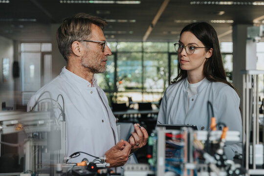 Scientist and researcher discussing data in laboratory with equipment