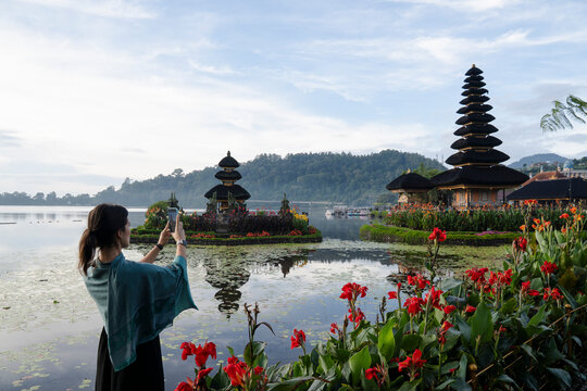 Traveler photographing traditional temple by lake in Bali Indonesia