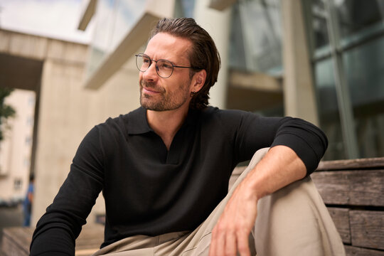 Portrait of a self confident hipster sitting on a bench outdoors