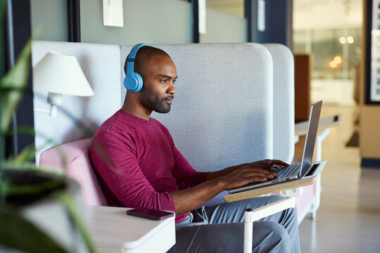 Young black casual man working on laptop in a coworking space