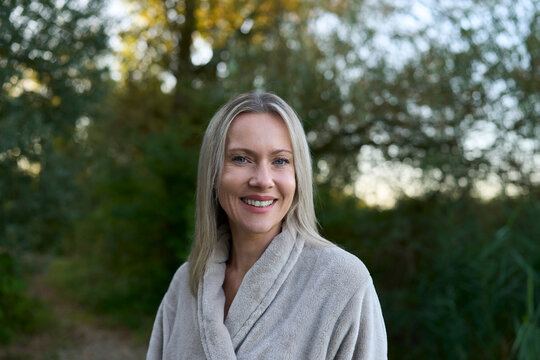 Smiling woman in bathrobe outdoors enjoying nature and wellness