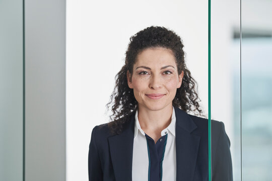 Smiling mature businesswoman near glass door in office