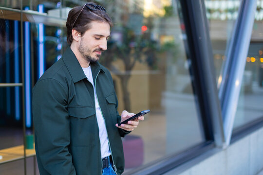 Casual freelancer texting on smartphone in urban setting