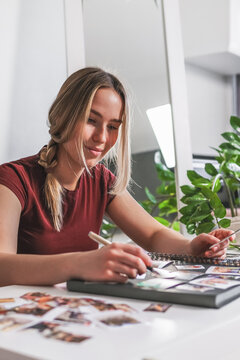 Young woman smiling while arranging a scrapbook photo album indoors