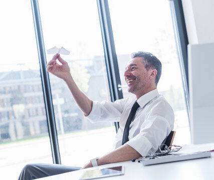Manager smiling and playing with paper airplane in the office