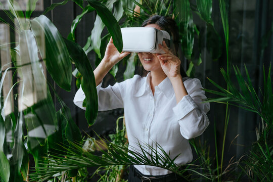 Smiling businesswoman wearing virtual reality simulator near plants