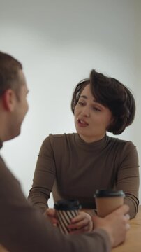 Happy Woman Engages in Lively Conversation Over Coffee with a Man at a Cafe