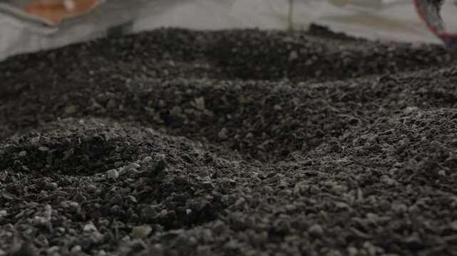 Dense pile of fine shredded grey plastic flakes collected inside bulk bag at recycling facility