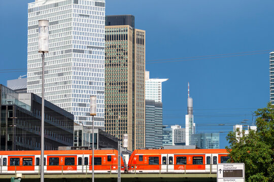 Urban infrastructure and transport shape a cityscape where commuter train follows railway tracks beneath the frankfurt skyline at daylight