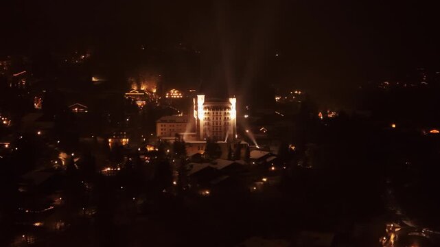Aerial: Gstaad Palace with snow at night in Gstaad, Canton of Bern, Switzerland, orbit drone shot