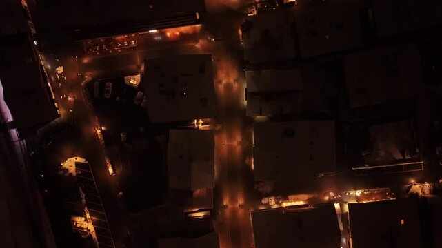 Aerial: Promenade Gstaad at night with snow and lights in Gstaad, Canton of Bern, Switzerland, top down drone shot