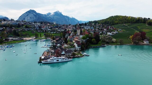 Aerial: Spiez castle, port, boats and Lake Thun during the day in Spiez, canton of Bern, Switzerland, establishing drone shot