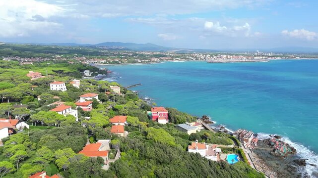 aerial panorama heading out to sea on the Mediterranean coastline and luxury homes of Castiglioncello, Italy, Tuscany