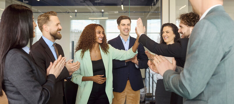 Business team colleagues celebrate success with office highfive. Partners in a group meeting applaud achievement, highlighting teamwork and trust. Concept of unity, achievement and collaboration.