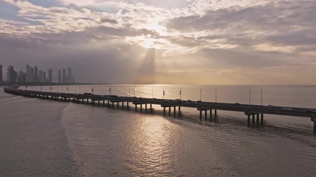 Aerial drone shot of the Corredor Sur in Panama City during sunrise showing the sun's rays in the distance