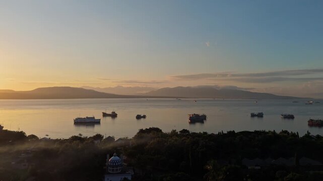 Peaceful morning landscape featuring misty coastline, traditional boats At Ketapang Harbour