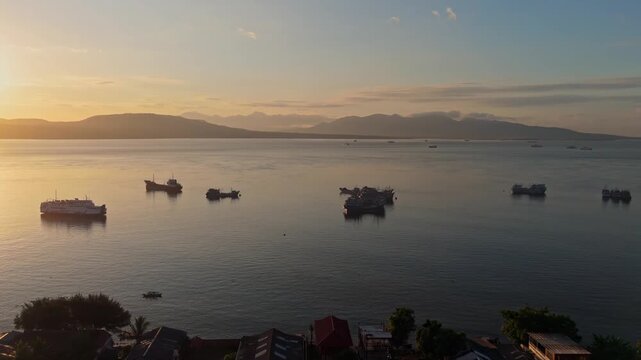Panoramic aerial of sunrise over Bali Strait with ferries and ships anchored in Ketapang Harbour