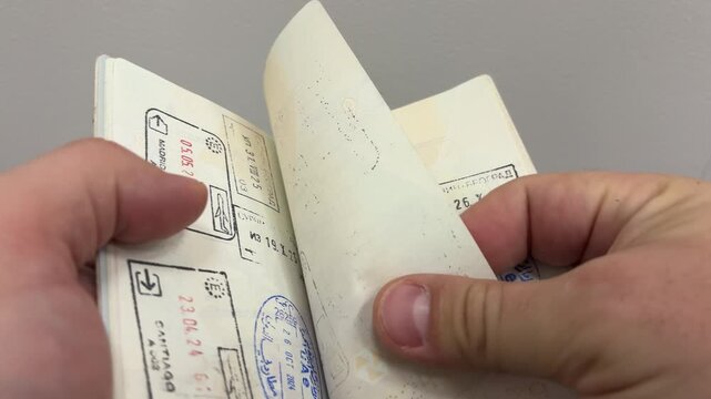 A detailed close-up video of a passport being flipped through, revealing pages filled with colorful travel stamps and visas. 