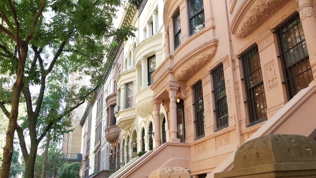 New York City townhouse buildings, brownstone row houses in Manhattan or Brooklyn, United States of America. Classic buildings on residential district street. Real estate property. Rowhouse townhome.
