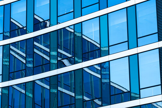 Contemporary building glass reflection on architecture facade with blue diagonal lines and grid forming a modern abstract geometric surface background
