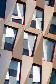 Contemporary building facade of windows with glass reflection where modern abstract geometry angles and symmetry create a striking architectural pattern background