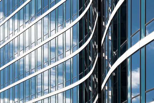 Contemporary glass reflection on architecture facade with blue skyline where modern abstract curves and lines shape a flowing urban pattern background