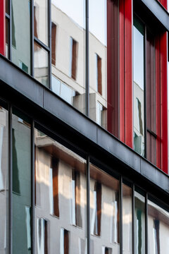 Contemporary building facade with red vertical lines and abstract pattern where modern architecture and glass reflection create a graphic urban background