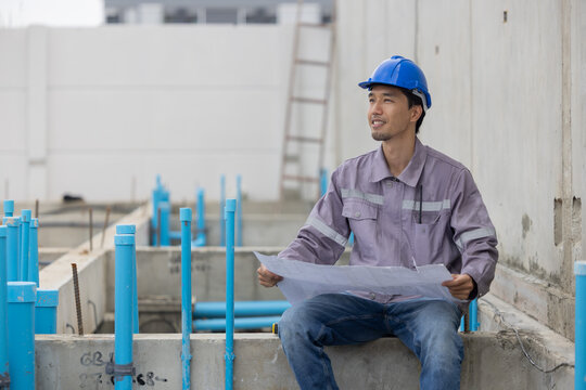 A construction manager in a safety helmet inspects a building site