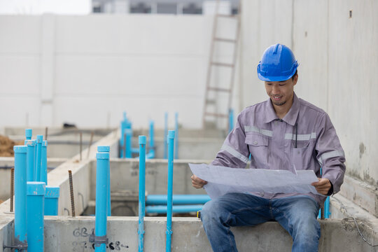 A construction manager in a safety helmet inspects a building site