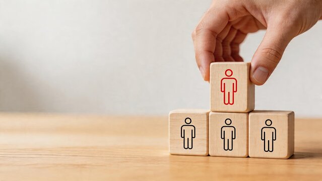 Business team building management hierarchy structure concept hand placing a red icon block on top of three wooden cubes with people icons representing staff leadership