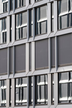 Ordered repetition defines this gray building as architecture facade and windows form a modern grid pattern with abstract rhythm and structure