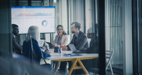Fototapeta na wymiar Business Team Meets in a Glass Conference Room to Review Dashboards, Discuss Financial Results, Set Revenue Targets, and Plan Strategy, Using Laptops and Tablets to Analyze Data, Share Insights