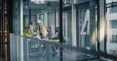 Executives and Engineers Meet in a Glass Office to Plan Construction Work, Review Digital Reports, Align Schedule and Budget, and Coordinate Safety, Quality Control, Resource Use, and Communication © Gorodenkoff
